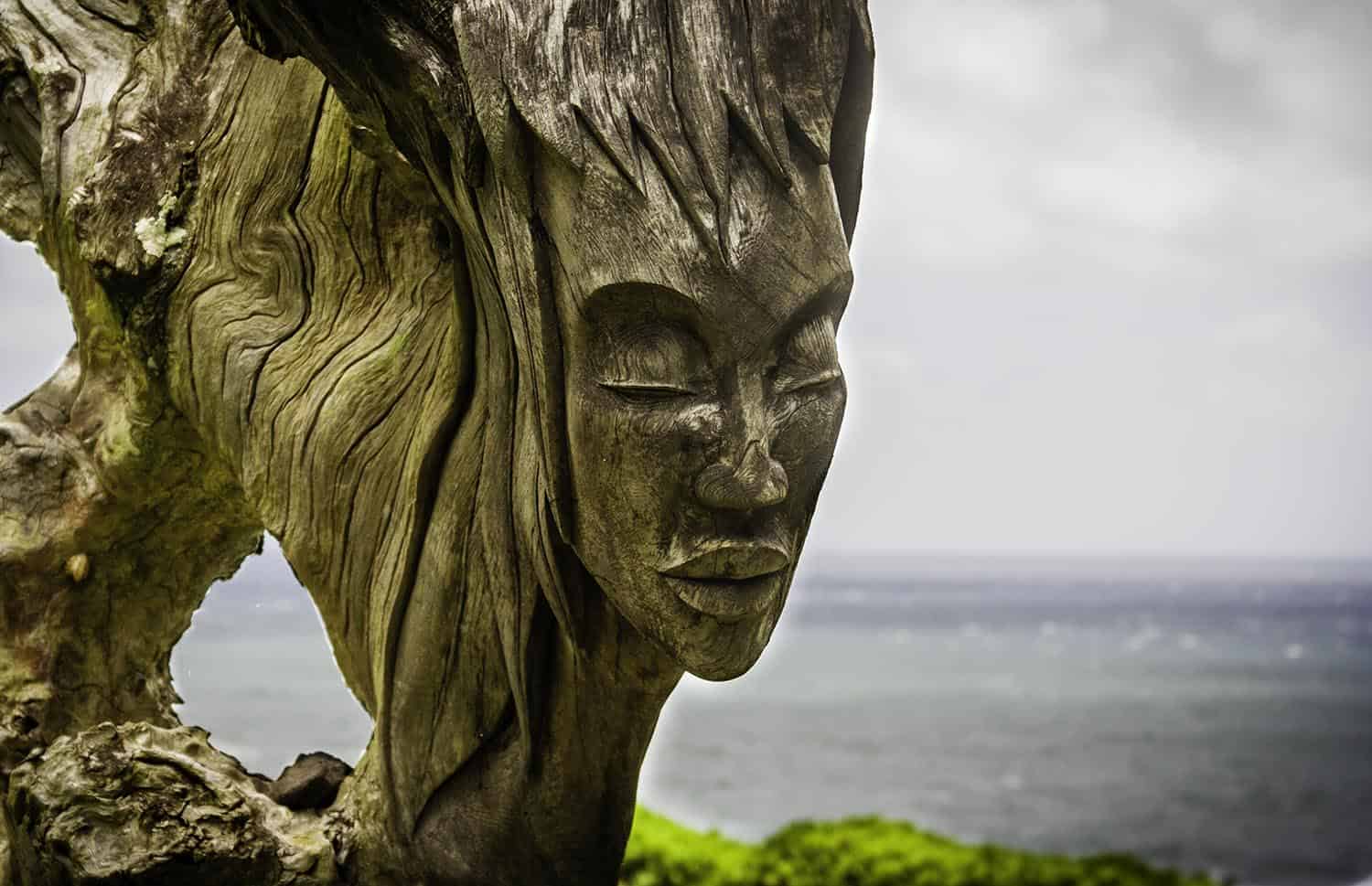 Detailaufnahme Holzskulptur einer Frau vor Ozean auf Maui, Hawaii